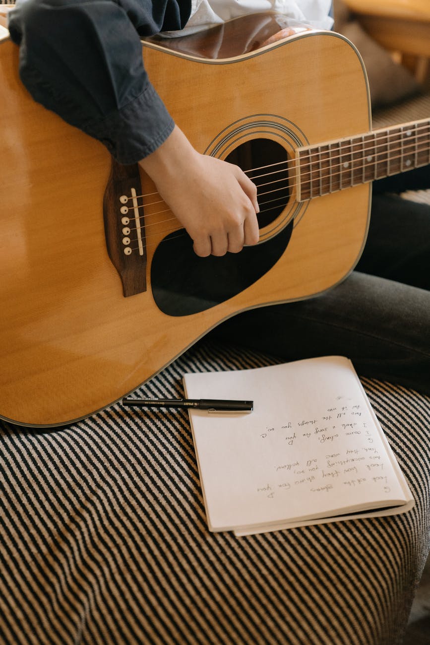 brown acoustic guitar on brown and black stripe sofa