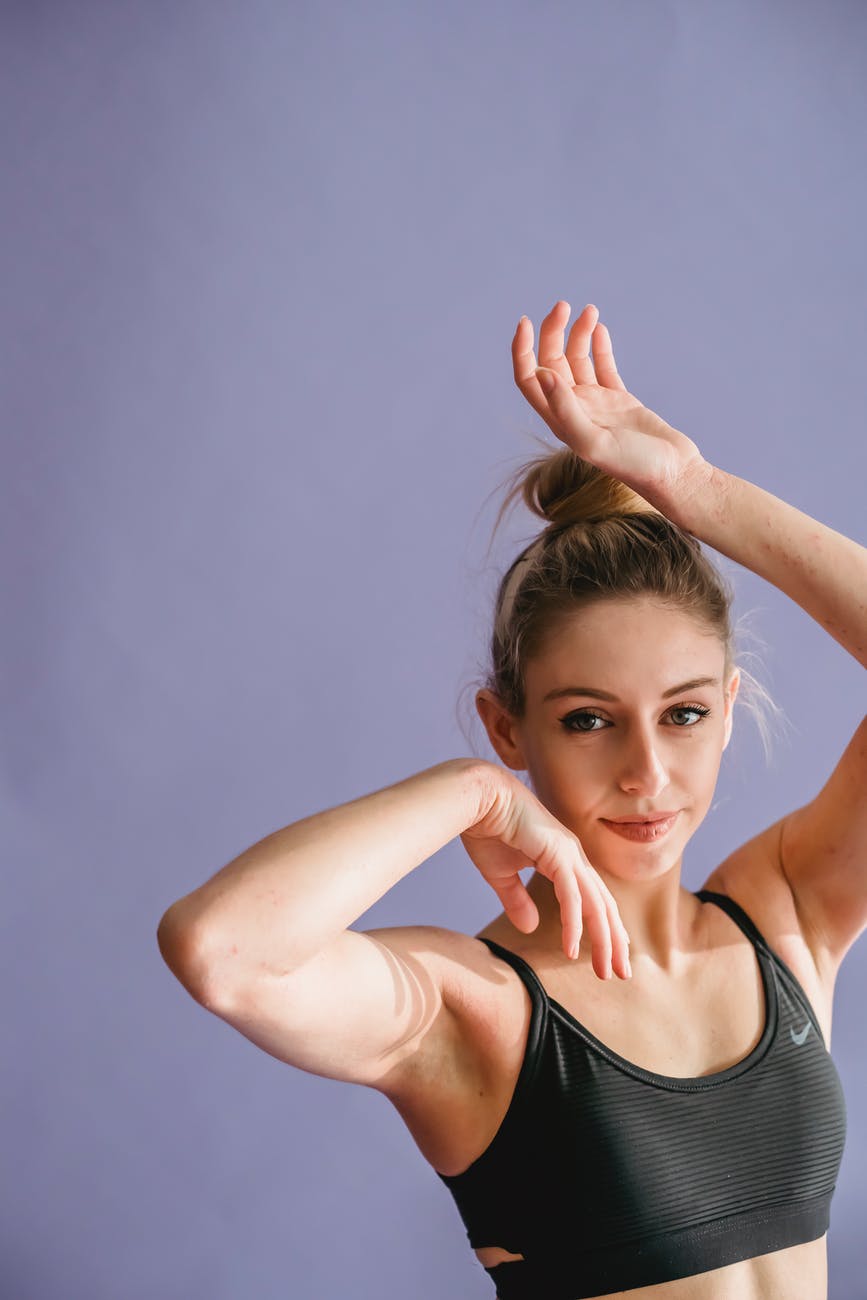 charming female dancing and looking at camera against purple background
