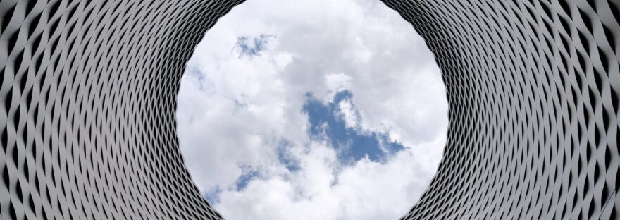 low angle photography of grey and black tunnel overlooking white cloudy and blue sky