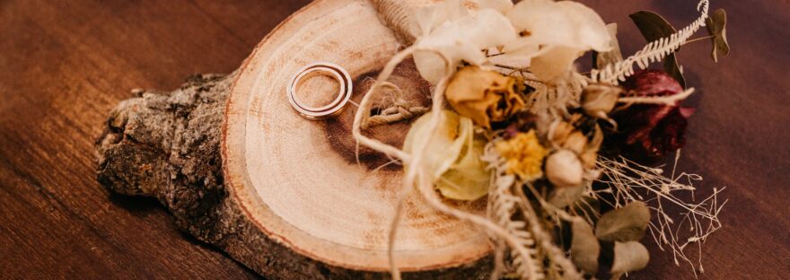 bouquet of dried flowers and wedding rings on wood