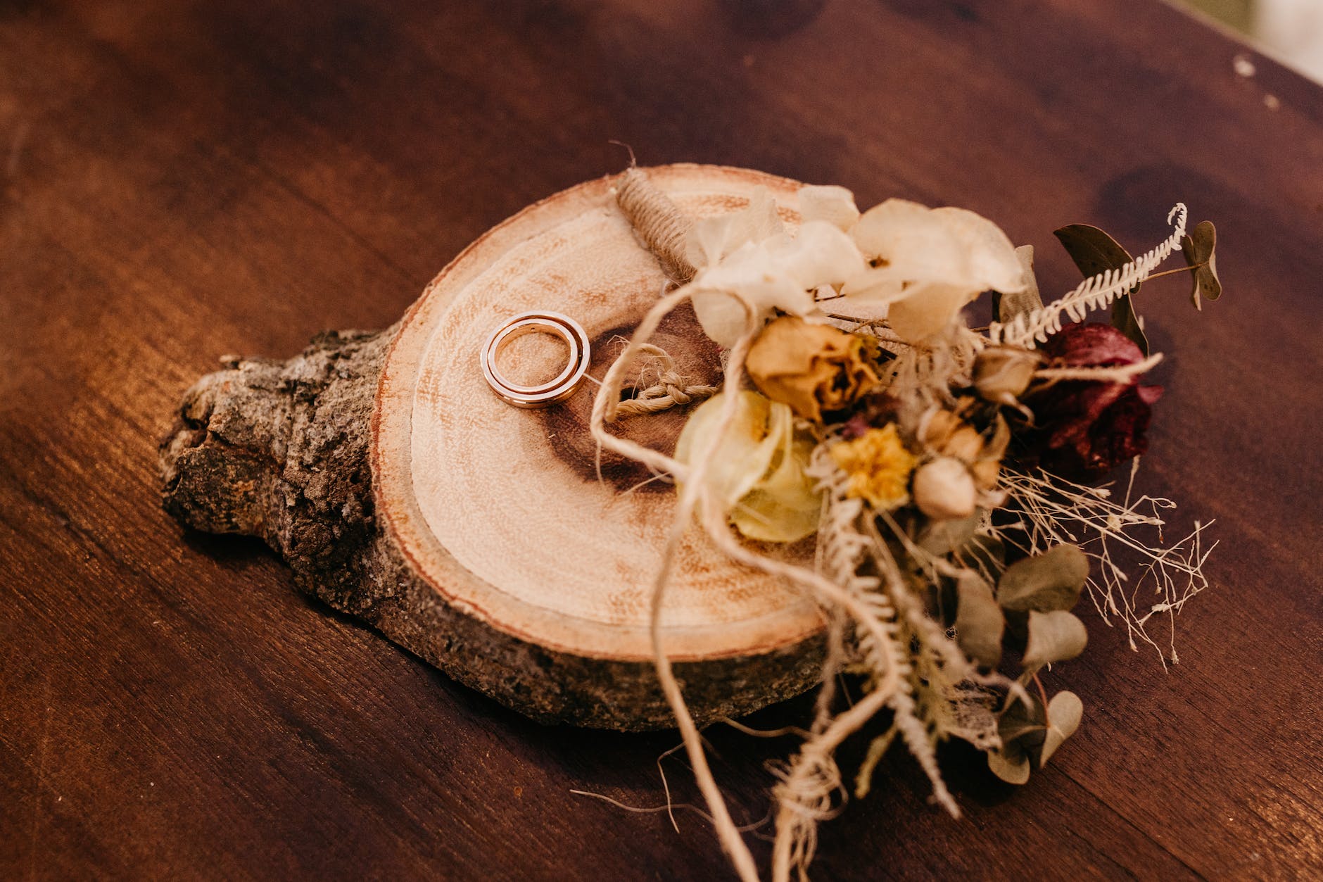 bouquet of dried flowers and wedding rings on wood